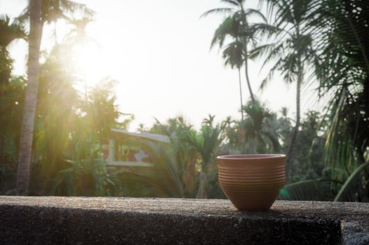 Coffee cup (Bhar) in sunset sunlight. Summer fresh cool look. Muddy mud tea cup made of clay for hot drink on roof beam of a residential building with bokeh city in the background.