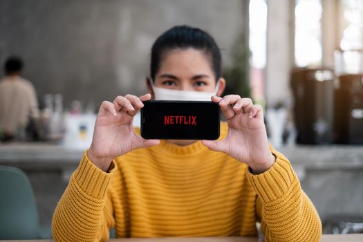 CHIANG MAI, THAILAND APR 14 2021 : Hand holding Apple iPhone with Netflix logo on a screen. Netflix is a global provider of streaming movies and TV series
