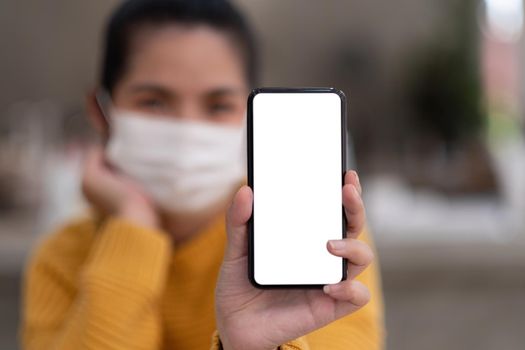 Mockup image of a beautiful woman wear mask while holding mobile phone with blank white screen