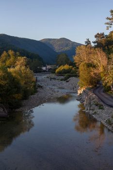 Landscape with mountains, river and trees in the sunset