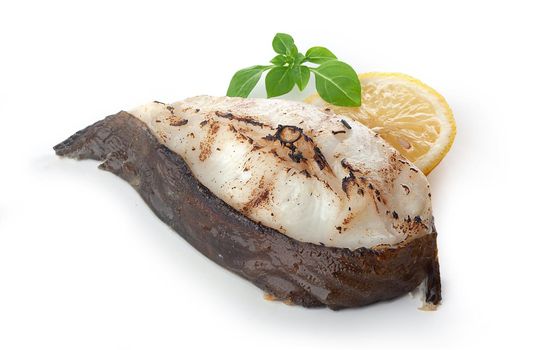 Isolated roasted catfish steak with basil and lemon