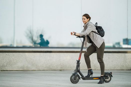 A young businesswoman with an electric push scooter going to work.