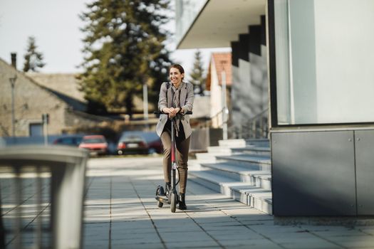 A young businesswoman going to work with an electric push scooter.