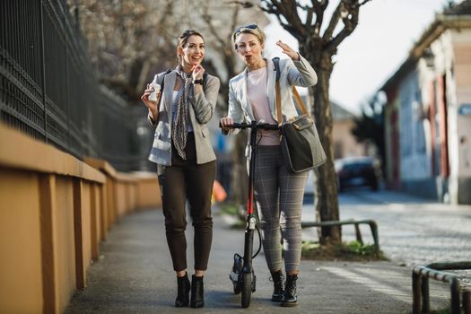 A two successful businesswomen having a quick break and chatting while walking through the city.