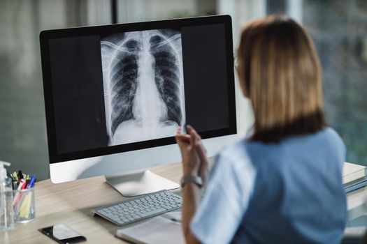 A female nurse is looking X-ray of a lungs on a computer in the hospital during COVID-19 pandemic.