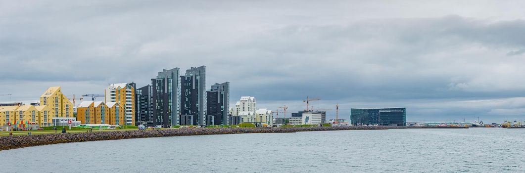 Panoramic view over Reykjavik business and touristic downtown, embankment, ocean, harbor and modern buildings at dramatic skyline but calm ocean, Iceland, summer