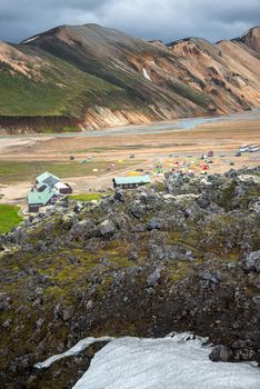 Surreal magic Icelandic landscape of colorful rainbow volcanic Landmannalaugar mountains, and a biggest camping site there with tourists and hikers, Iceland, summer