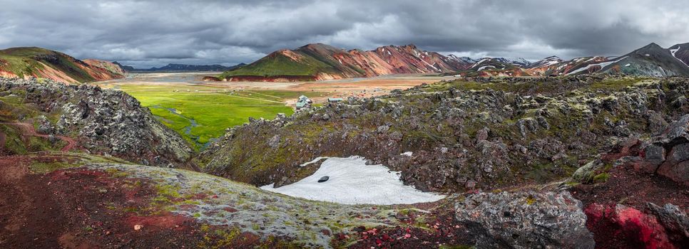 Panoramic surreal magic Icelandic landscape of colorful rainbow volcanic Landmannalaugar mountains, and a biggest camping site there with tourists and hikers, Iceland