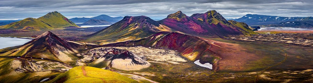 Panoramic unreal magic Icelandic landscape of colorful rainbow volcanic Landmannalaugar mountains, red and pink volcanic crater Stutur at famous Laugavegur hiking trail with dramatic sky, Iceland