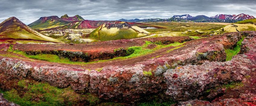 Panoramic surreal magic Icelandic landscape of colorful rainbow volcanic Landmannalaugar mountains, red and pink volcanic crater Stutur at famous Laugavegur hiking trail with dramatic sky, Iceland