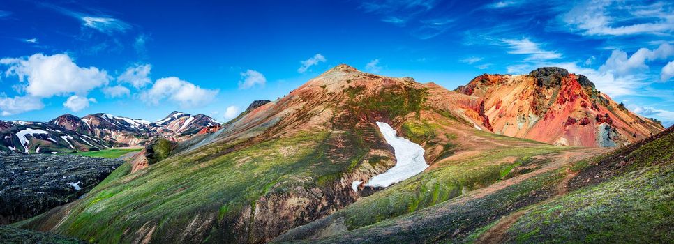 Panoramic true Icelandic landscape view of colorful rainbow volcanic Landmannalaugar mountains, red and pinky volcanic crater and famous Laugavegur hiking trail at blue sky, Iceland