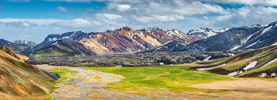 Panoramic true Icelandic landscape view of colorful rainbow volcanic Landmannalaugar mountains, volcanoes, valleys and famous Laugavegur hiking trail at blue sky, Iceland