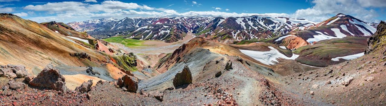 Panoramic true Icelandic landscape view of colorful rainbow volcanic Landmannalaugar mountains, volcanoes, valleys and famous Laugavegur hiking trail at blue sky, Iceland