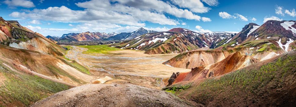 Panoramic true Icelandic landscape view of colorful rainbow volcanic Landmannalaugar mountains, volcanoes, valleys and famous Laugavegur hiking trail at blue sky, Iceland