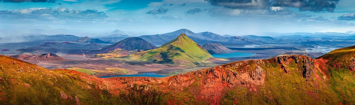 Panoramic landscape view of colorful rainbow volcanic Landmannalaugar mountains and famous Laugavegur hiking trail, with dramatic sky and snow in Iceland