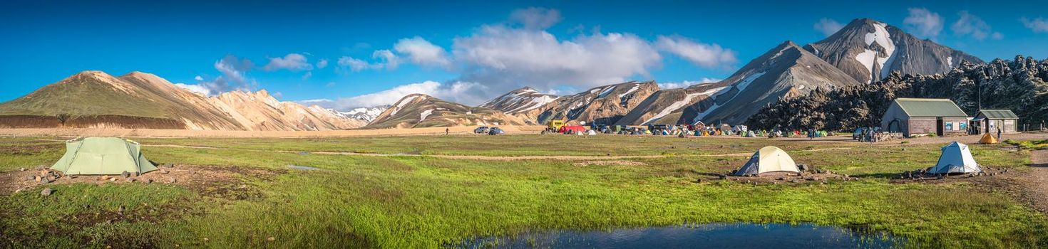 Panoramic view of colorful volcanic Landmannalaugar region and camping site at blue sky in Iceland, summer time, dramatic scene