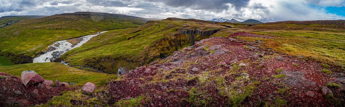 Panoramic view over beautiful colorful Icelandic landscape with Faxi waterfall, ancient moss and lichen, tundra flowers and meadow fields near Snaefell volcano and Laugarfell area in Iceland