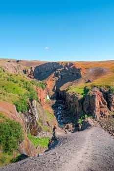 Beautiful and tall Icelandic waterfall Hengifoss and hiking trail to it, Iceland, sunny day, blue sky