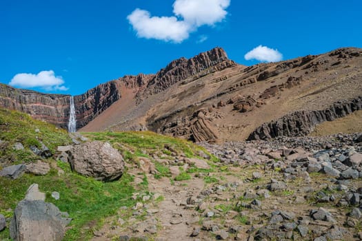 Beautiful and tall Icelandic waterfall Hengifoss and hiking trail to it, Iceland, sunny day, blue sky