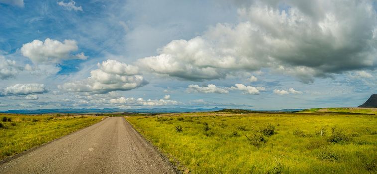 Panoramic view over lonely road through rough and colorful Icelandic landscape, Iceland, summer, blue sky with beautiful clouds