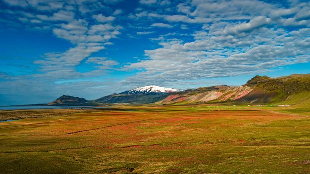 Panoramic view over covered with snow Snaefellsjoekull mountain summit and Icelandic colorful and wild landscape with cloud twists at summer, Iceland