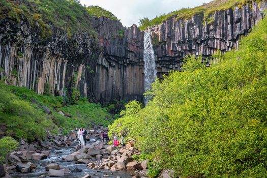 Touristic wedding ceremony at Svartifoss waterfall with black basalt columns in South Iceland