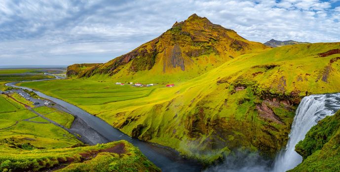 Panoramic view over camping site with tents and cars in front of famous Skogarfoss waterfall, while hiking in Iceland, summer, scenic view