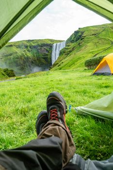 Camping site with tents in front of famous Skogarfoss waterfall, while hiking in Iceland, summer, scenic view