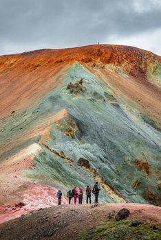 Iconic colorful rainbow volcanic mount Brennisteinsalda in Landmannalaugar mountains and group of hikers in Iceland, summer, dramatic scenery