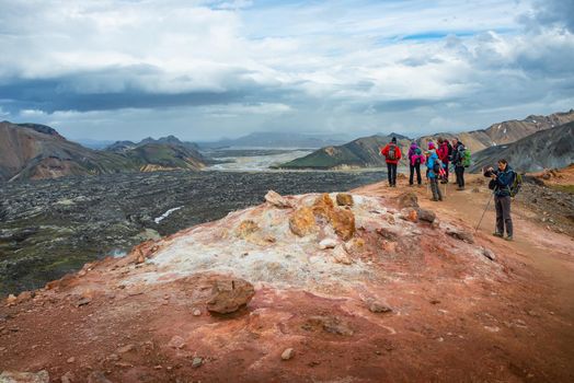 Panoramic view over iconic colorful rainbow volcanic mountains Landmannalaugar, Laugahraun lava field and group of hikers in Iceland, summer, dramatic scenery