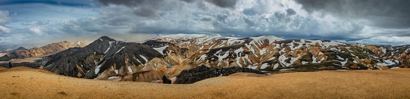 Panoramic view over iconic colorful rainbow volcanic mountains Landmannalaugar and two hikers in Iceland, summer, dramatic scenery