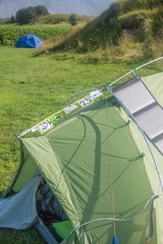 Green tent of a hiker with many stay stickers and a solar panel in Iceland