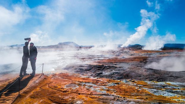 Panoramic view of geothermal active zone Hverir near Myvatn lake with two travelers in Iceland