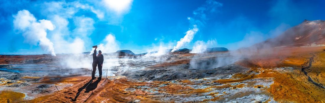 Panoramic view of geothermal active zone Hverir near Myvatn lake with two travelers in Iceland