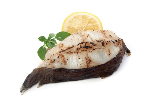 Isolated roasted catfish steak with basil and lemon