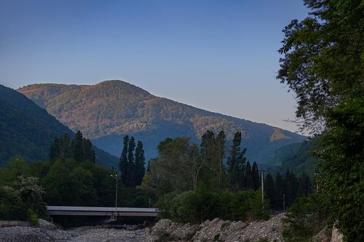 Mountains, trees and mountain river at the sunset