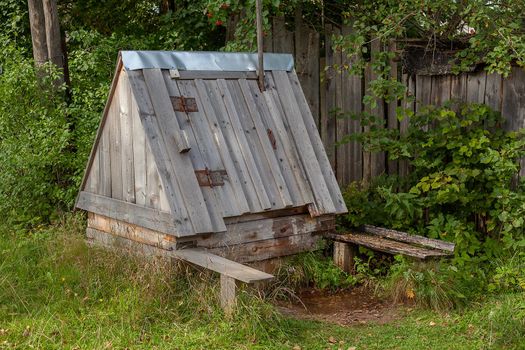 Wooden rustic well with crane in summer