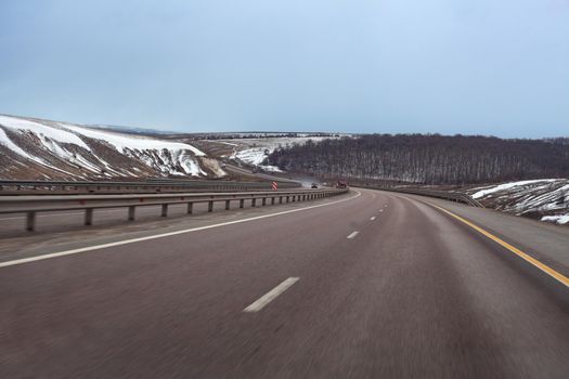 Road trough snowy hills in early spring