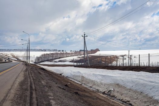 Road in the snowy field in early spring