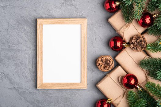 Christmas holidays composition with picture frame mockup. Red baubles, gifts and fir-tree branches.