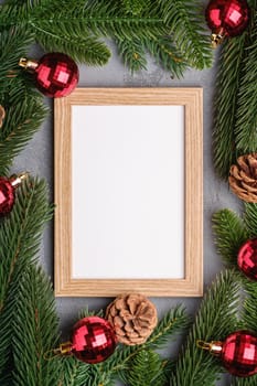 Christmas holidays composition with picture frame mockup. Red baubles and fir-tree branches.