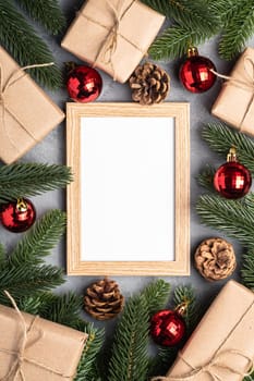 Christmas holidays composition with picture frame mockup. Red baubles, gifts and fir-tree branches.