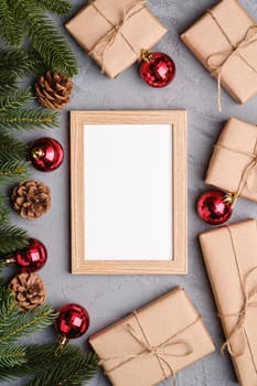 Christmas holidays composition with picture frame mockup. Red baubles, gifts and fir-tree branches.