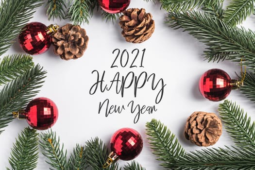 2021 Happy New Year holidays text with red baubles, pine cones and fir-tree branches.