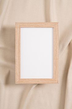 Wooden picture frame with white mockup on a beige textile