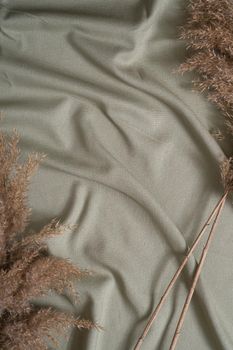 Green neutral colored textile, linen fabric near to decor dry pampas grass