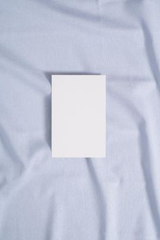 White blank paper card mockup on a blue neutral colored textile
