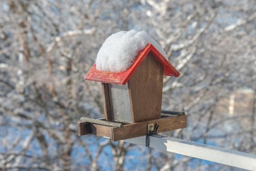 Empty bird feeder with no food inside and covered with snow. Concept, help for small city birds to survive during winter season