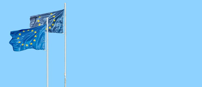 Banner with two blue flags with stars in circle of the European Union (EU) and at blue sky, with copy space, details, closeup