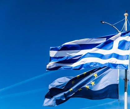 European political news, grexit and nation concept - Flags of Greece and European Union on blue sky background, politics of Europe
